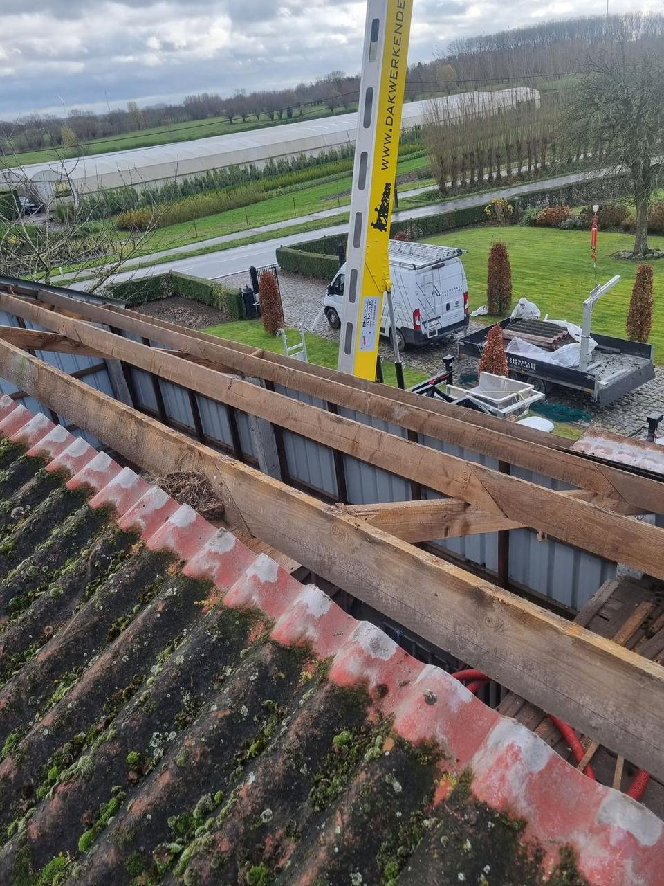 De oude asbest golfplaten op de houten structuur