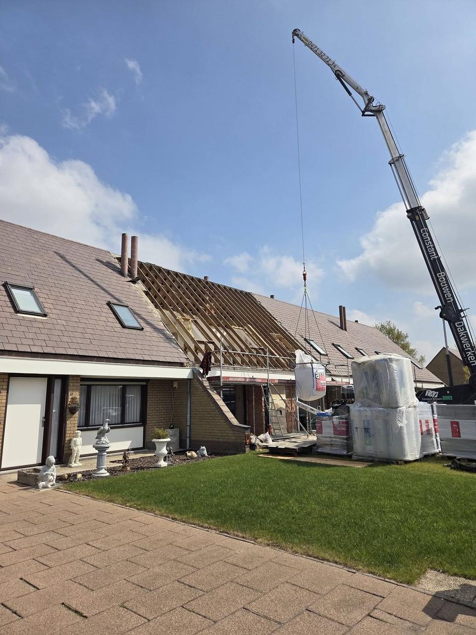 Materialen worden met een kraan op het dak gezet