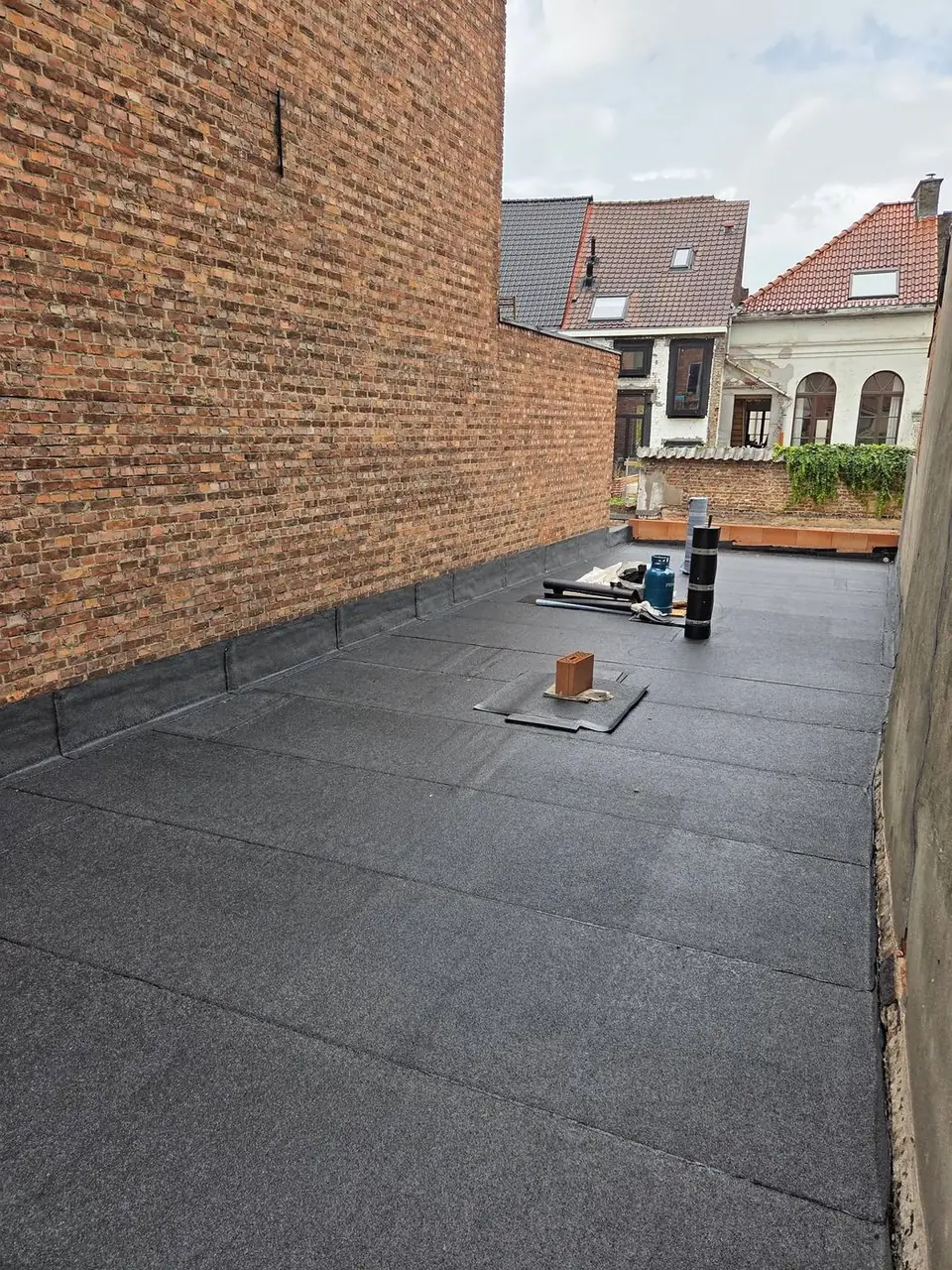 Afgewerkt plat dak met zicht op de achterliggende woningen