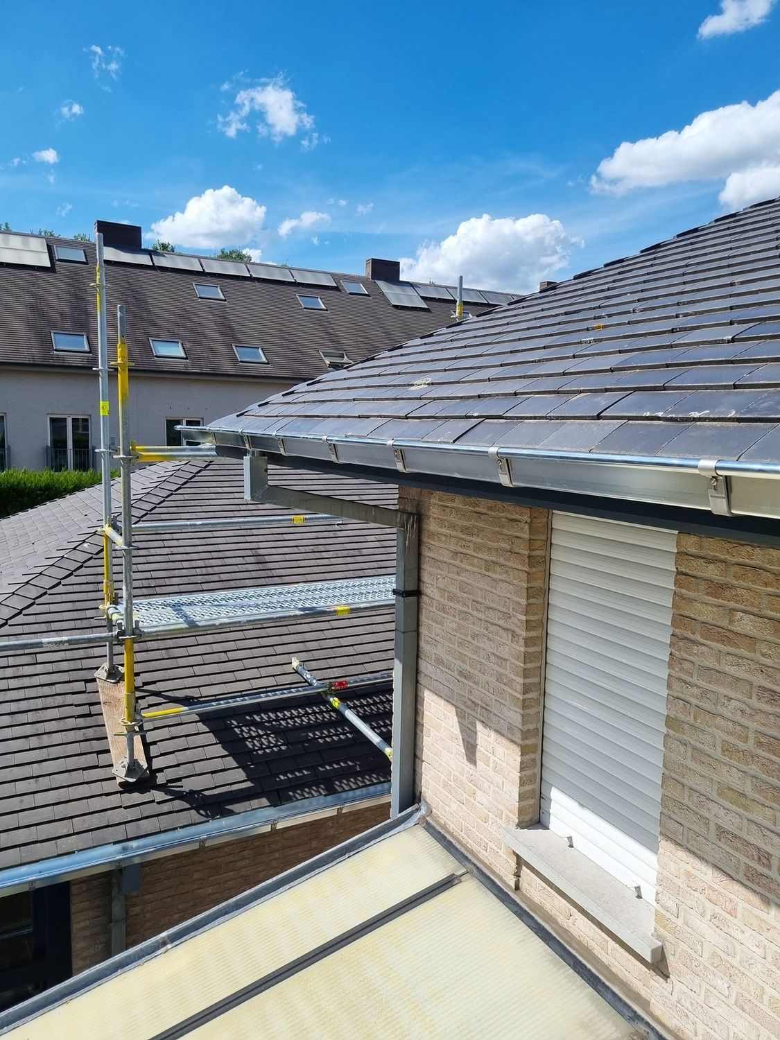 Nieuwe zinken dakgoot met afvoer langs de dakrand van een woning